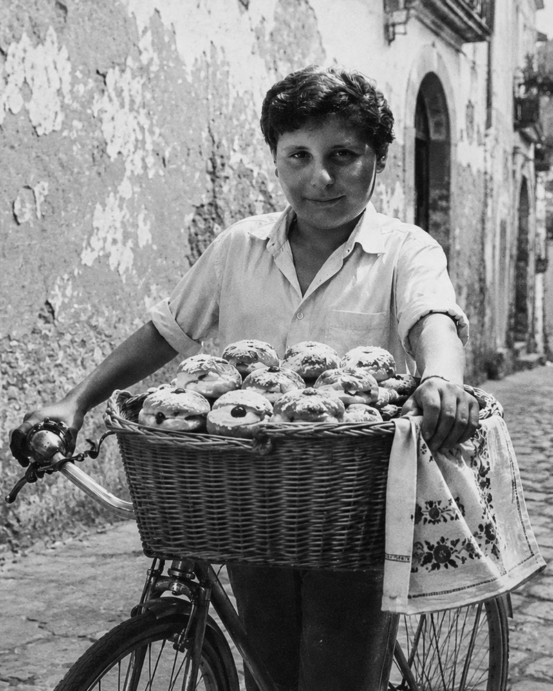 A boy in Southern Italy with a basket of fresh pastries on the front of his bicycle